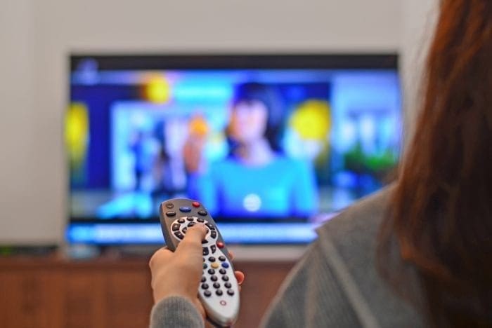 woman flipping through channels with remote