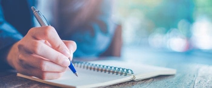 man writing in notebook