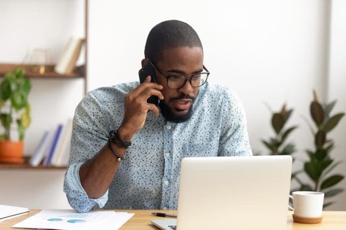 man on the phone looking at laptop