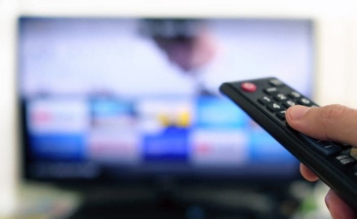 Man flipping through TV channels with remote