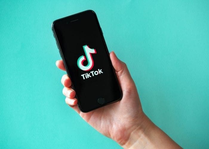 Hand holding phone Tik Tok logo